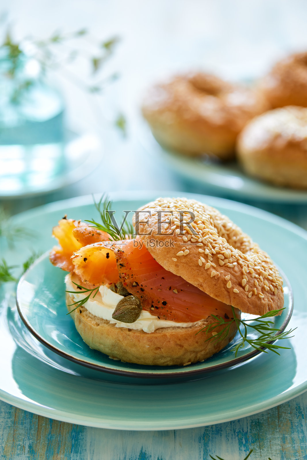 传统的百吉饼配上奶油芝士,熏鲑鱼和新鲜的莳萝,放在一个蓝色的盘子里照片摄影图片
