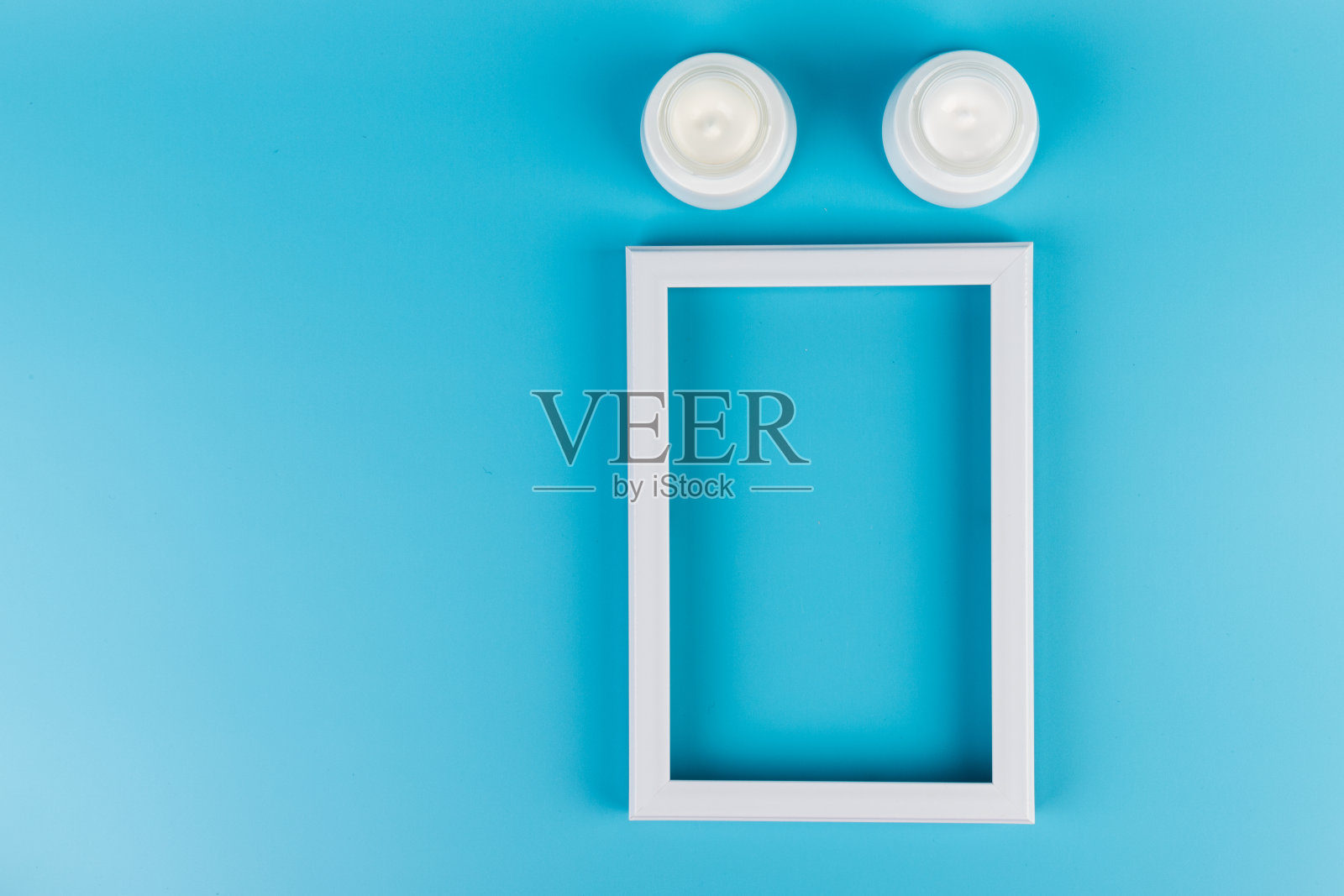 白色的护肤霜和蓝色背景的白色相框。照片摄影图片