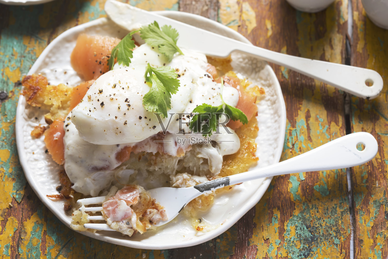皇家Rosti鸡蛋。土豆煎饼配熏鲑鱼,荷兰酱,荷包蛋和香菜照片摄影图片