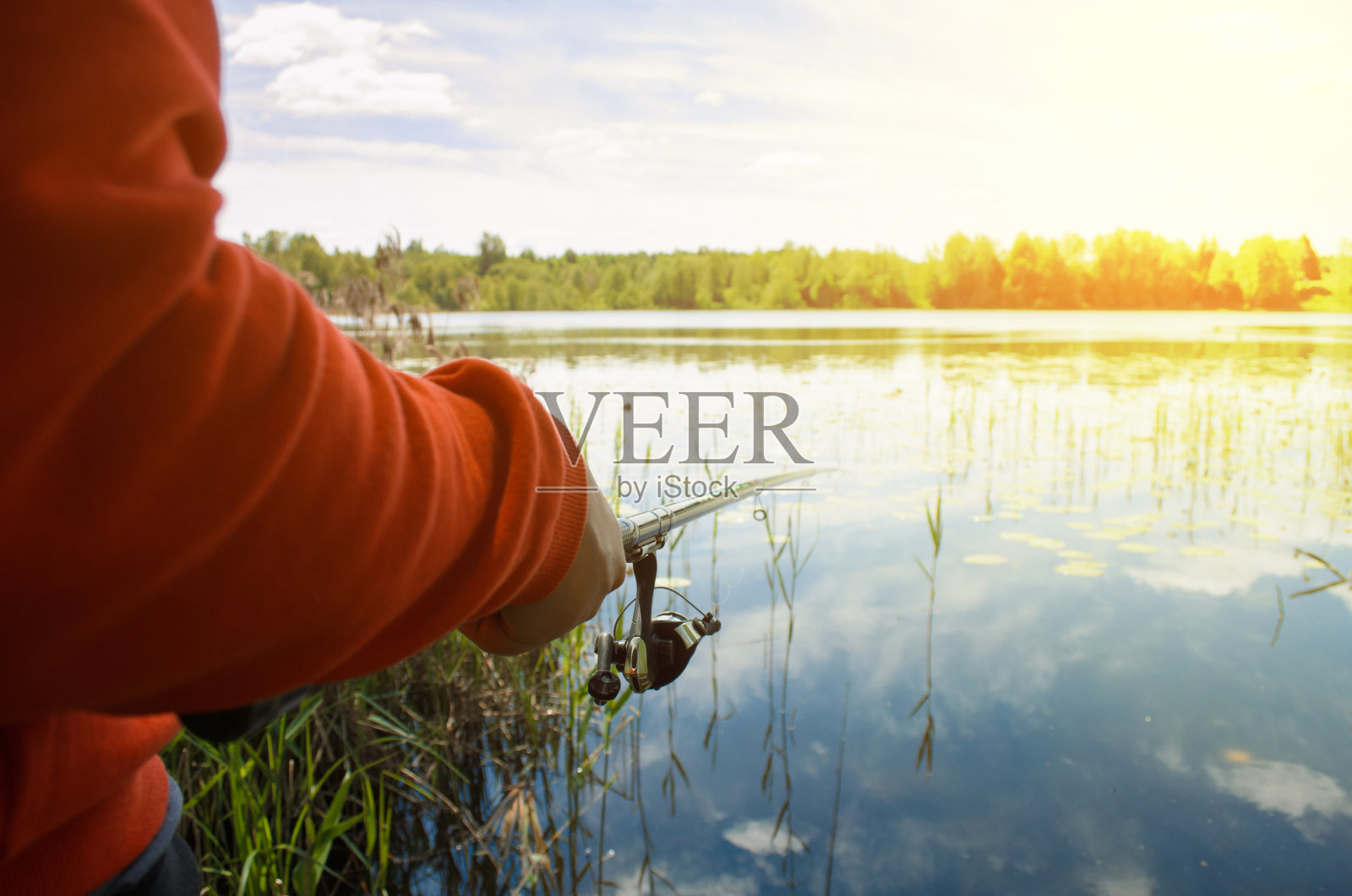 在湖上钓鱼。一个渔夫拿着钓竿,在外面钓鱼的特写。户外活动。有选择性的重点照片摄影图片
