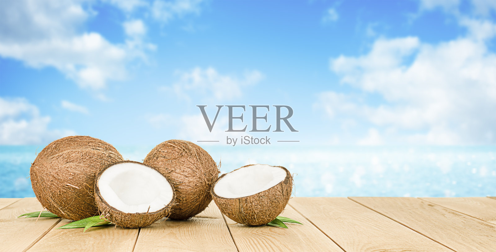 两个完整的椰子和两半的椰子放在一张木桌上照片摄影图片