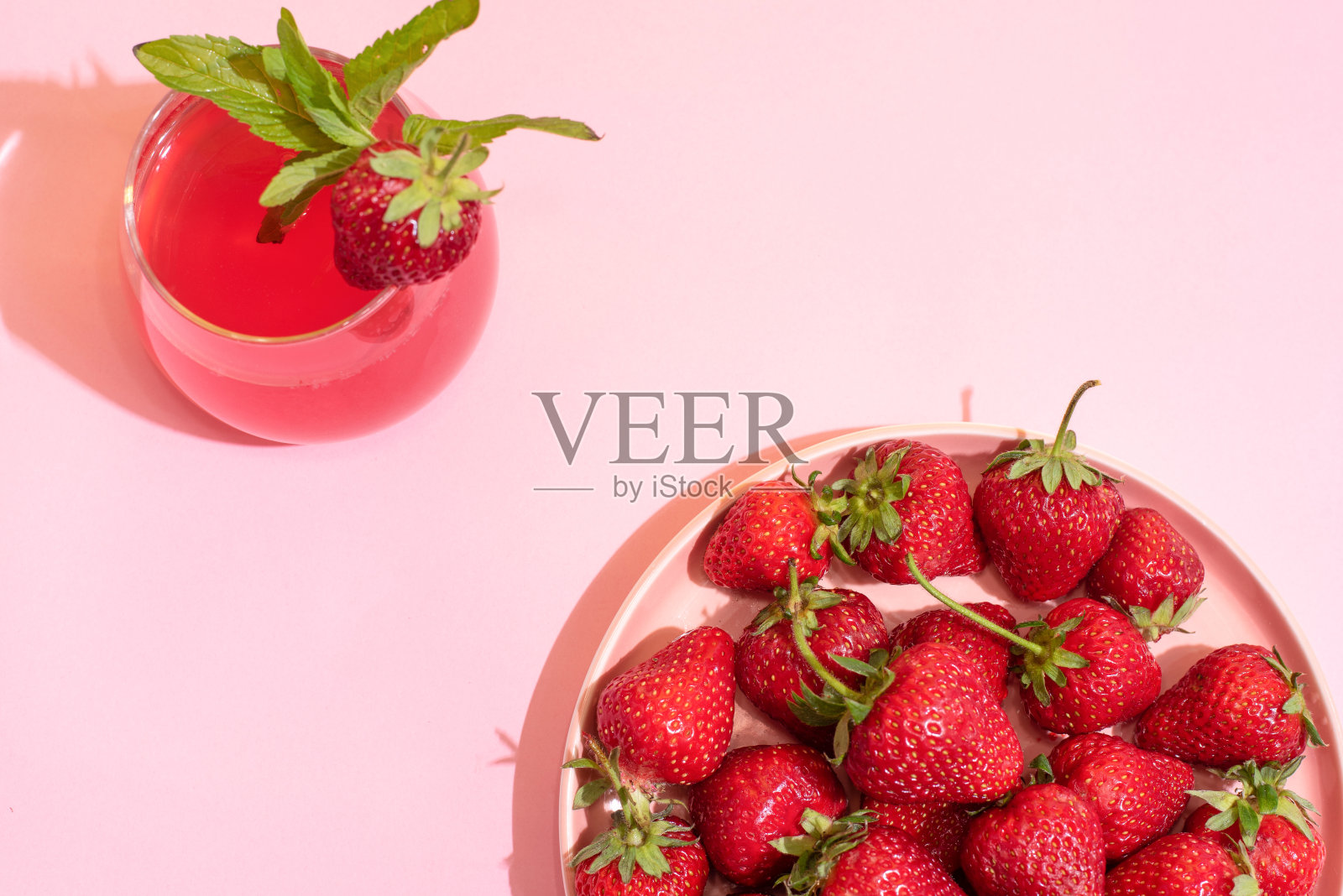 盘子与成熟的草莓和一杯草莓柠檬水在粉红色的背景,俯视图,夏天的概念。照片摄影图片