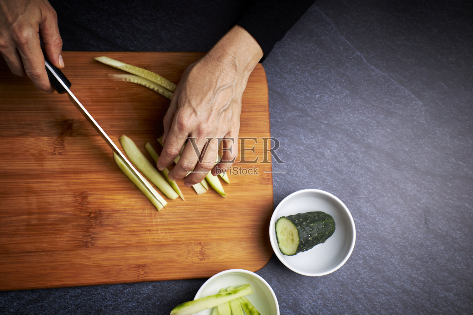 用刀把黄瓜切成条,在黑板上做寿司。亚洲食品的概念照片摄影图片