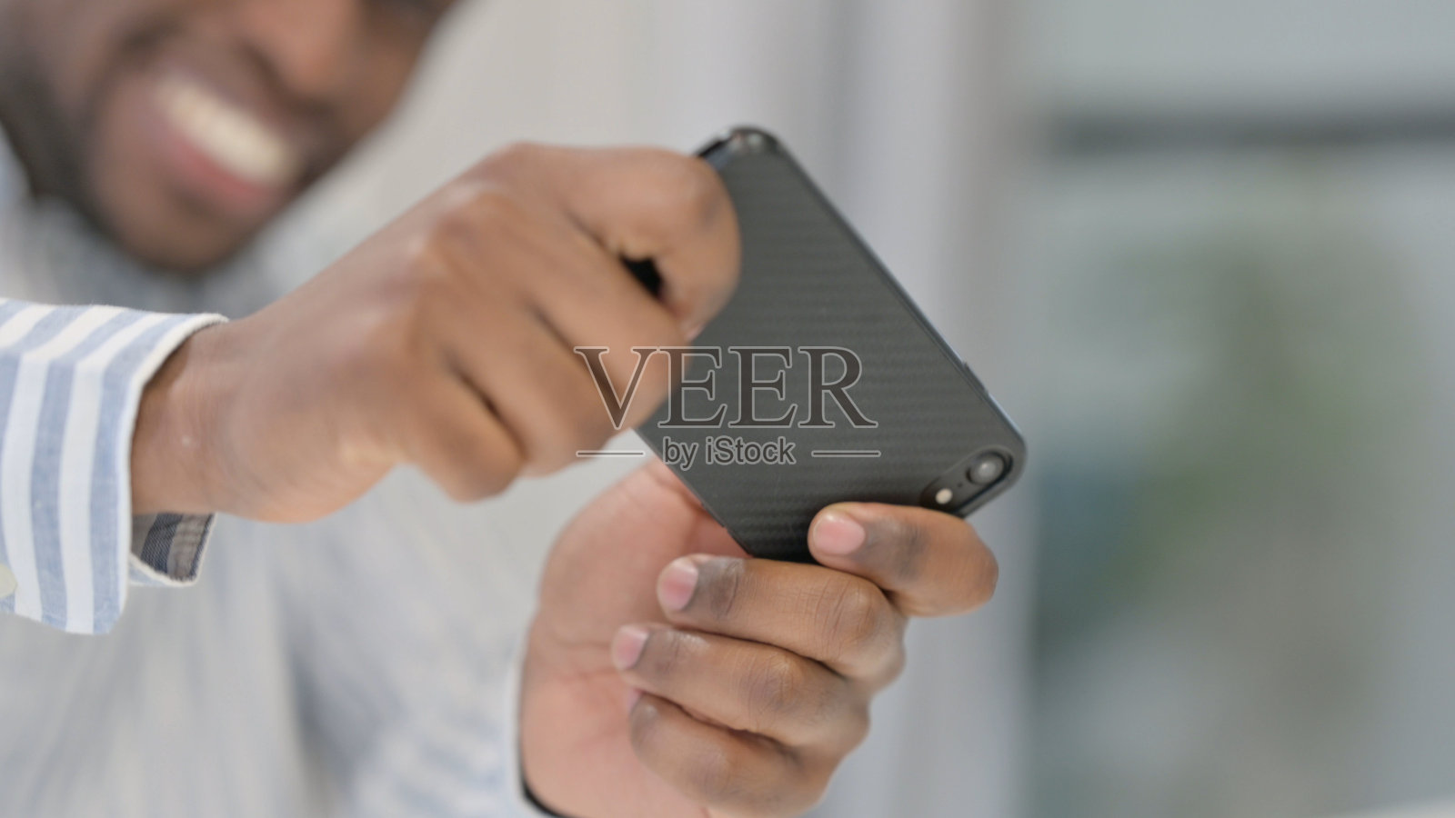 非洲人在智能手机上玩游戏的特写照片摄影图片