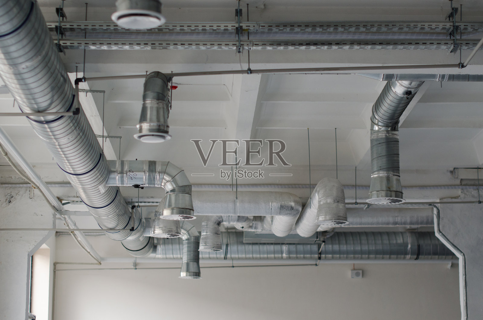 室内装修前,空调和暖通系统安装在裸天花板下。气流和通风系统。工业通风管道系统。照片摄影图片