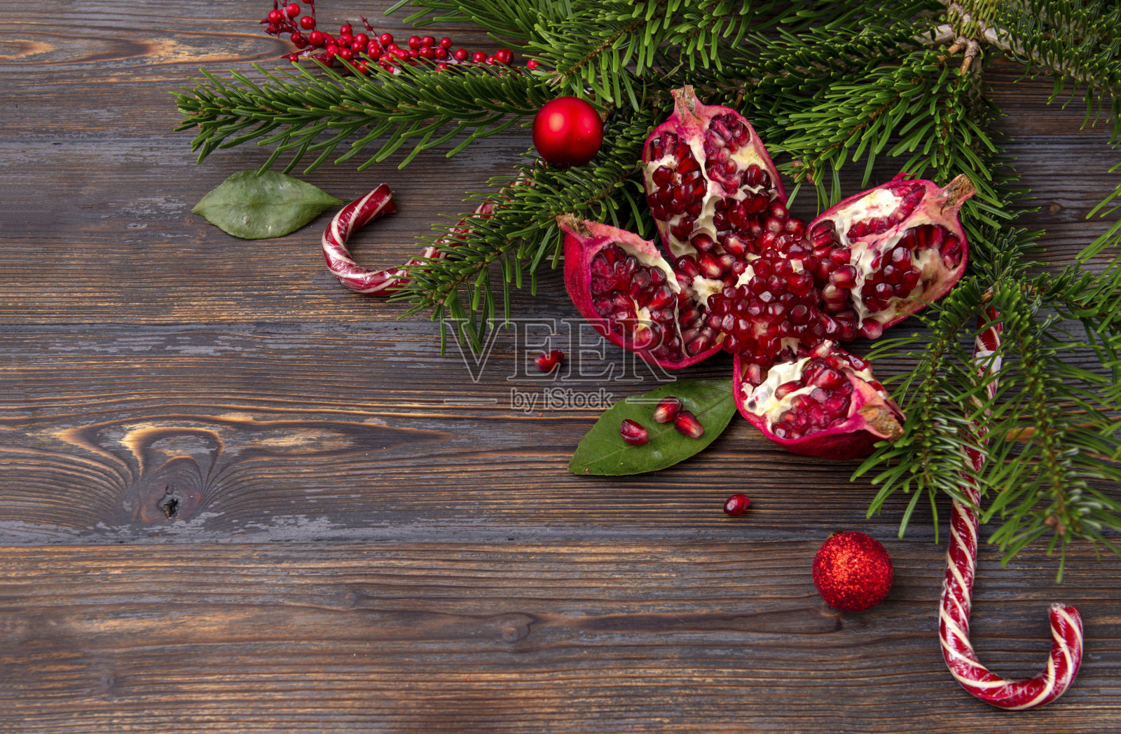 成熟的红石榴,冷杉树枝圣诞球,棒棒糖在一个棕色的木制背景顶视图照片摄影图片