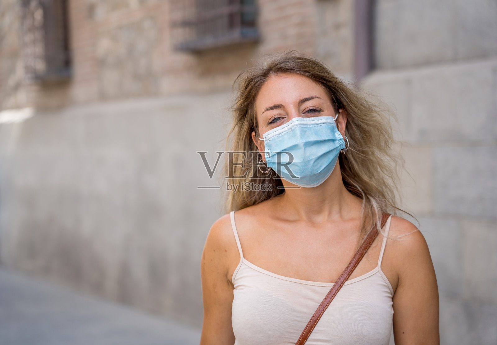 在城市街道上戴着防护面罩的年轻女子。新冠肺炎疫情后的新常态生活、暑假、旅游等正面形象。照片摄影图片