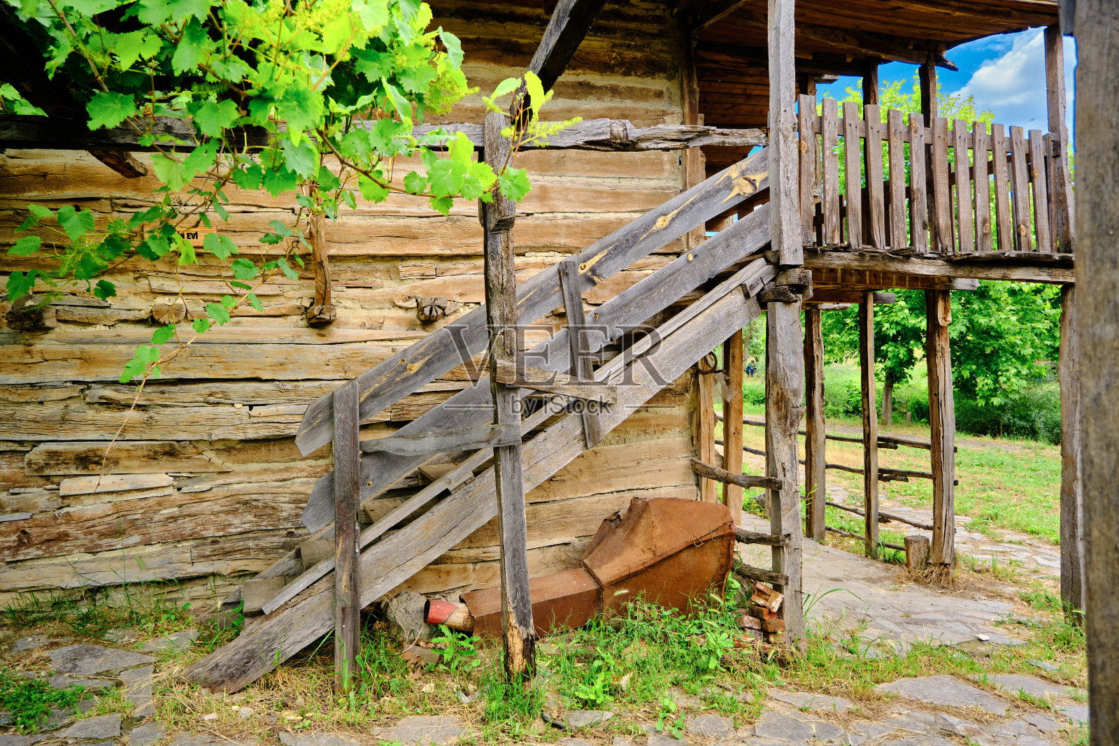 古老的废弃的棕色土地村庄的家,绿色的葡萄和楼梯建立在自然的石头地面。照片摄影图片