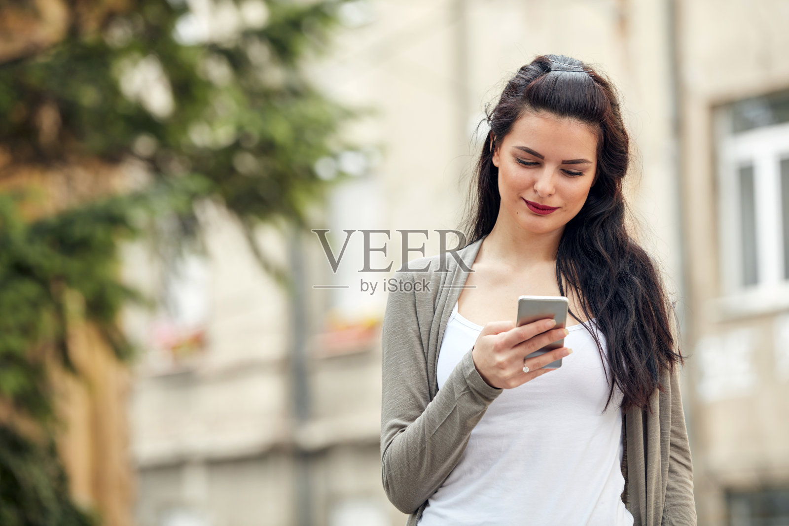 年轻可爱的女性在街上使用智能手机。照片摄影图片
