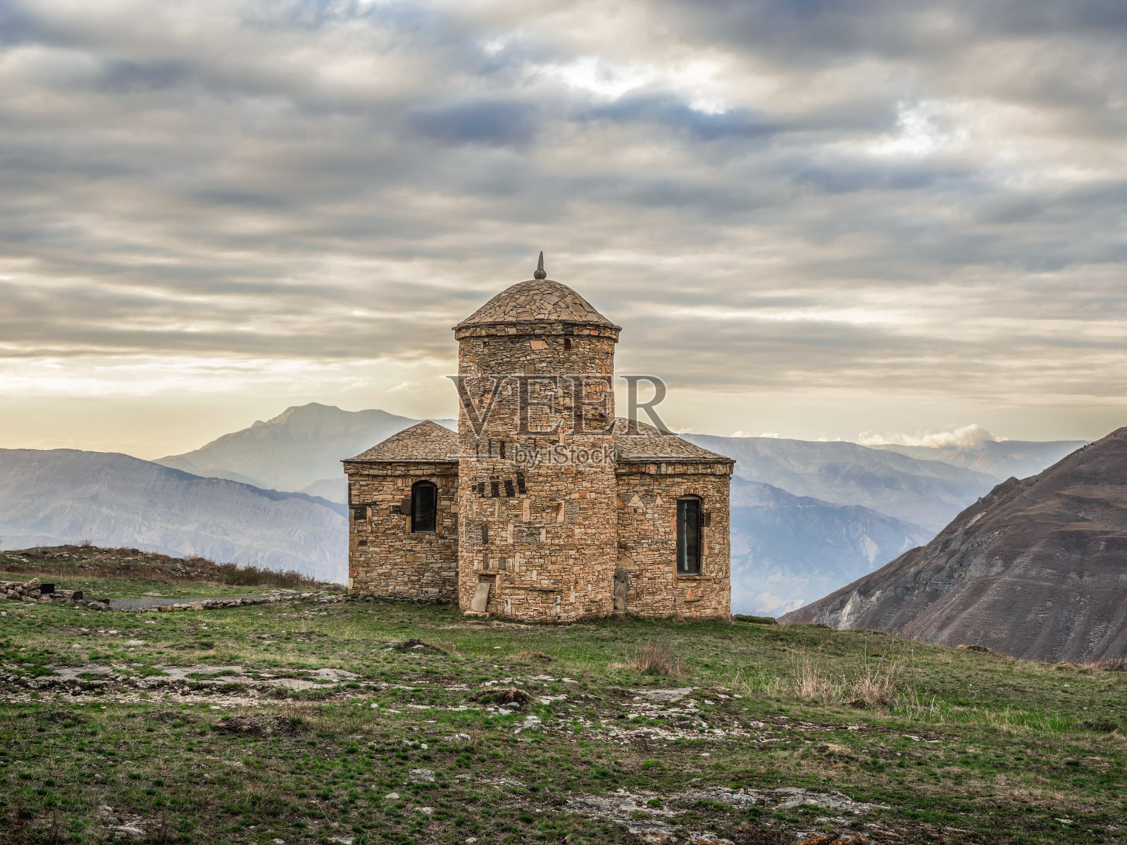 在戏剧性的天空背景上的石头清真寺。傍晚的阳光明媚地照在古老的石砌清真寺上。Hunzah。达吉斯坦。照片摄影图片
