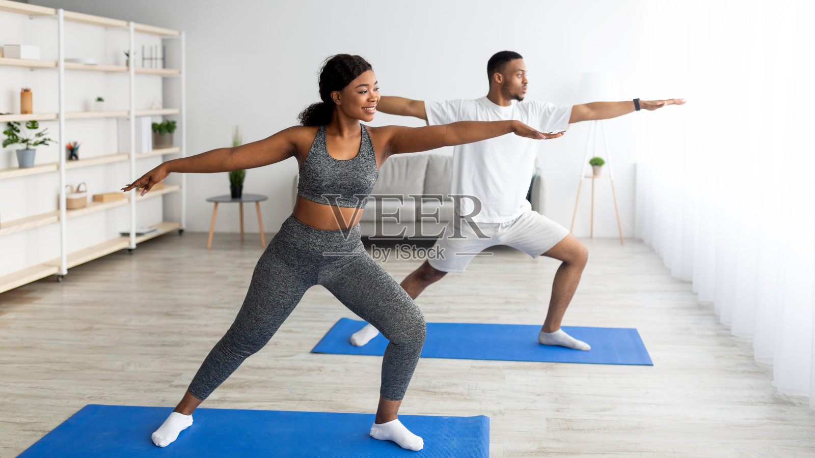力量瑜珈练习。适合黑人夫妇站在战士的姿势,在运动垫在家里锻炼,复制空间照片摄影图片