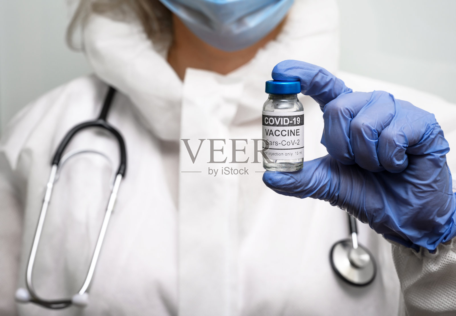 医生和COVID-19疫苗瓶,身着个人防护服的女医生手持冠状病毒疫苗照片摄影图片