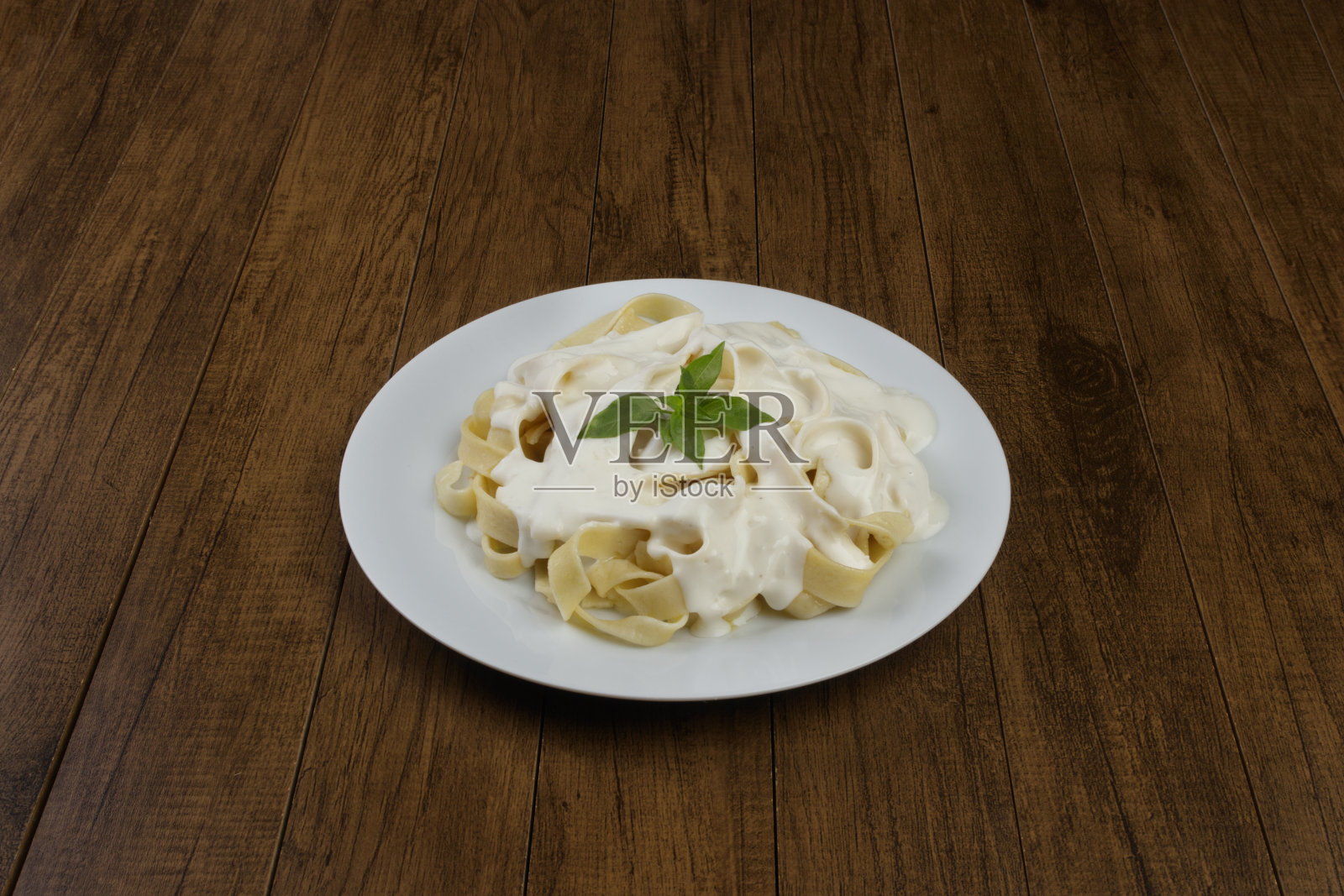 意大利宽面条配白汁和罗勒叶。白酱意大利面。中心有食物,还有发短信的空间。照片摄影图片