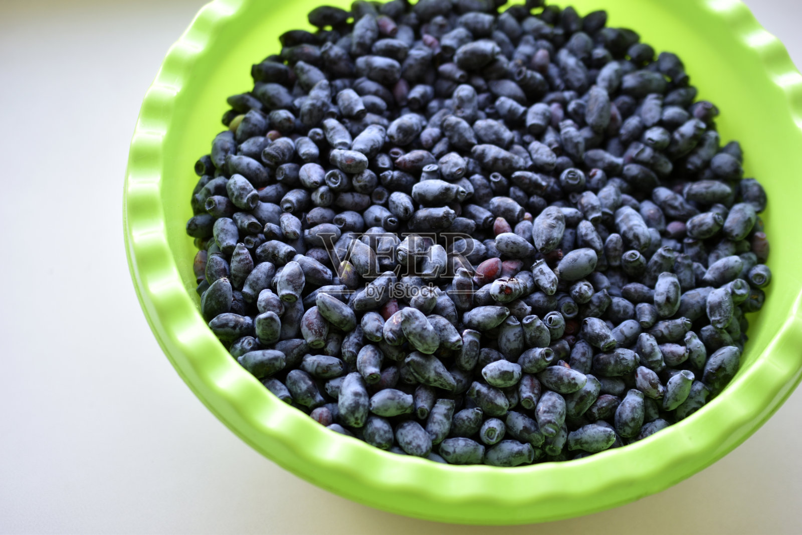 蓝色的新鲜金银花浆果在绿色的花盆照片摄影图片