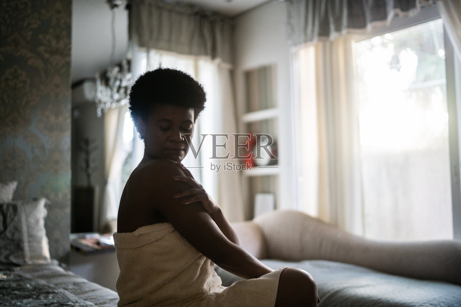 成熟的女人在家里把面霜涂在肩上照片摄影图片