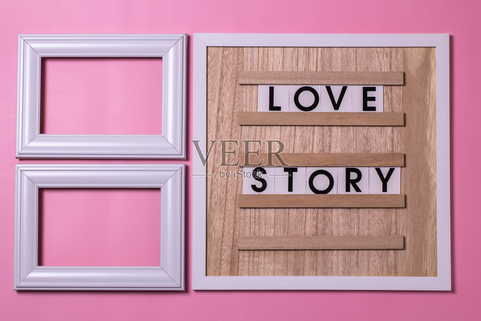 爱情故事与相框,躺在木板上的粉红色背景上。照片摄影图片