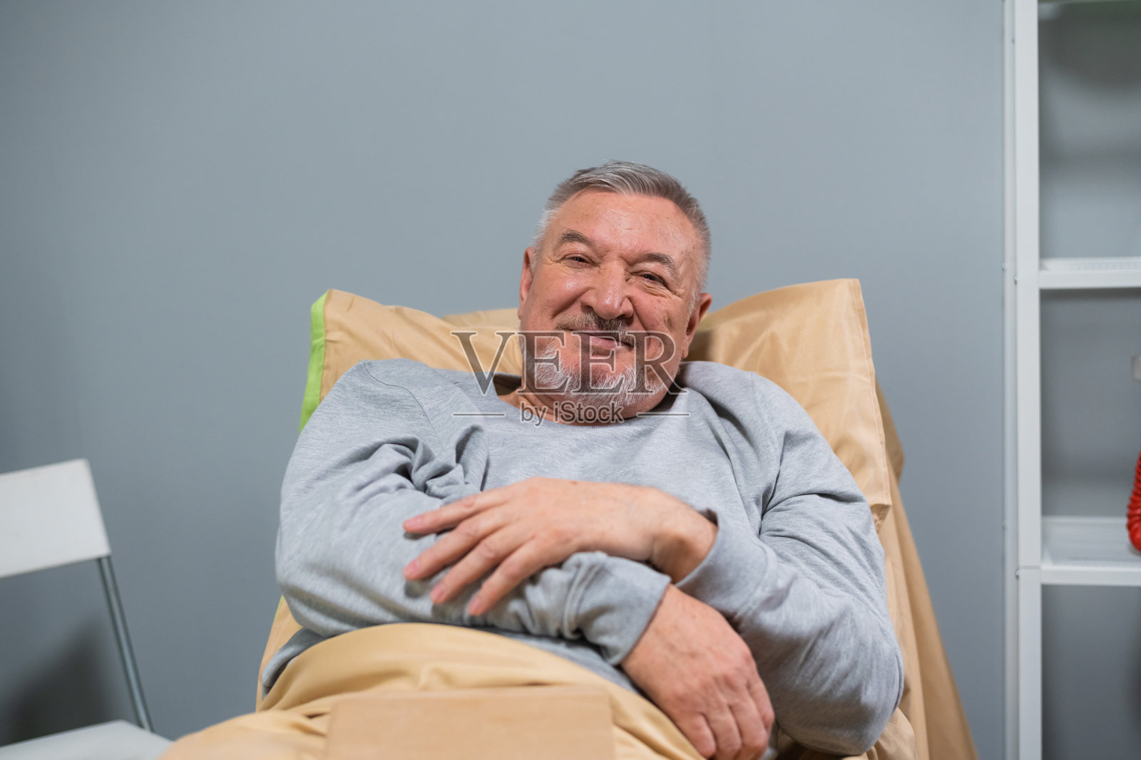坐在床上看着镜头的微笑老人肖像照片摄影图片