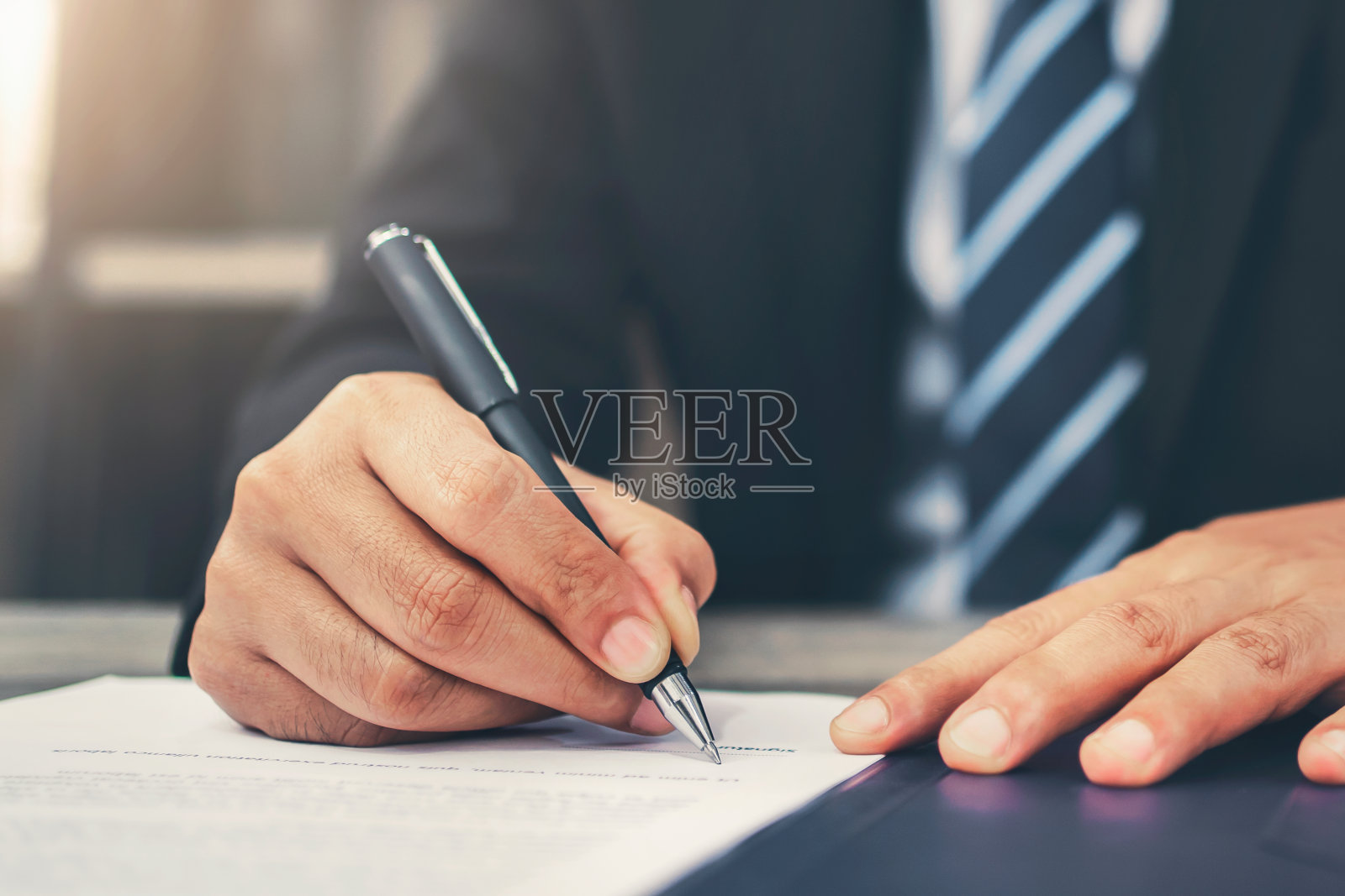 商人在办公室的文件上写签名照片摄影图片