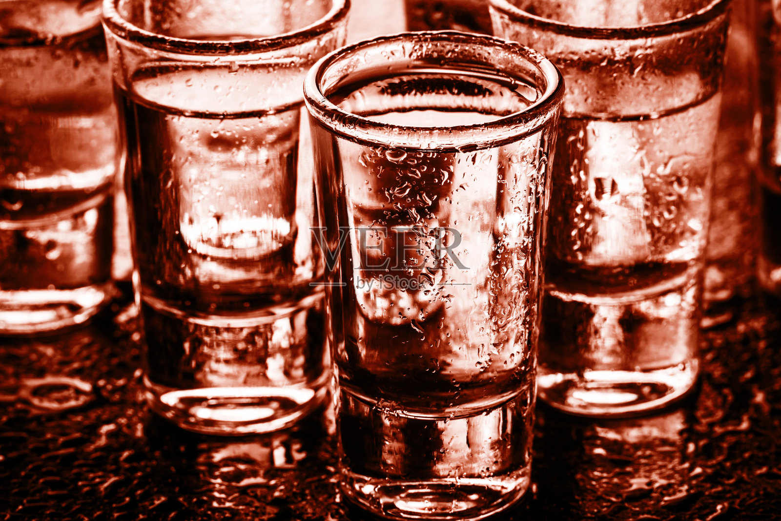 玻璃的伏特加。酒精饮料排成一行的质地。周末派对背景。湿吧表面反射。照片摄影图片