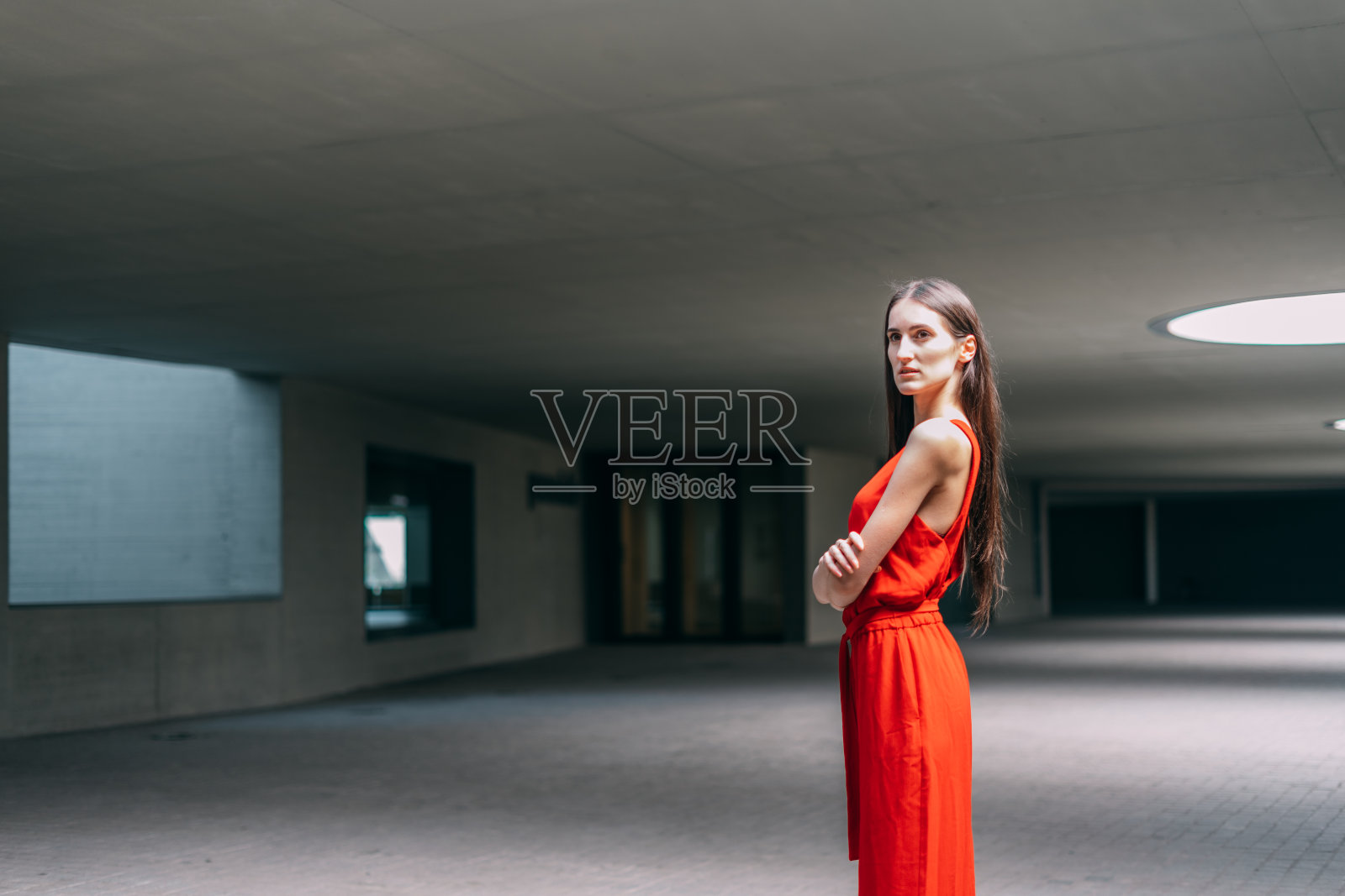 穿着红衣服的女商人,双臂交叉,看着室内的摄像机照片摄影图片