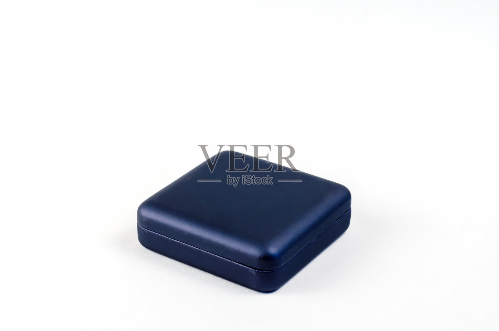 白色背景上的方形塑料小礼盒。封闭的蓝色盒子,戒指,耳环,袖扣和其他珠宝照片摄影图片