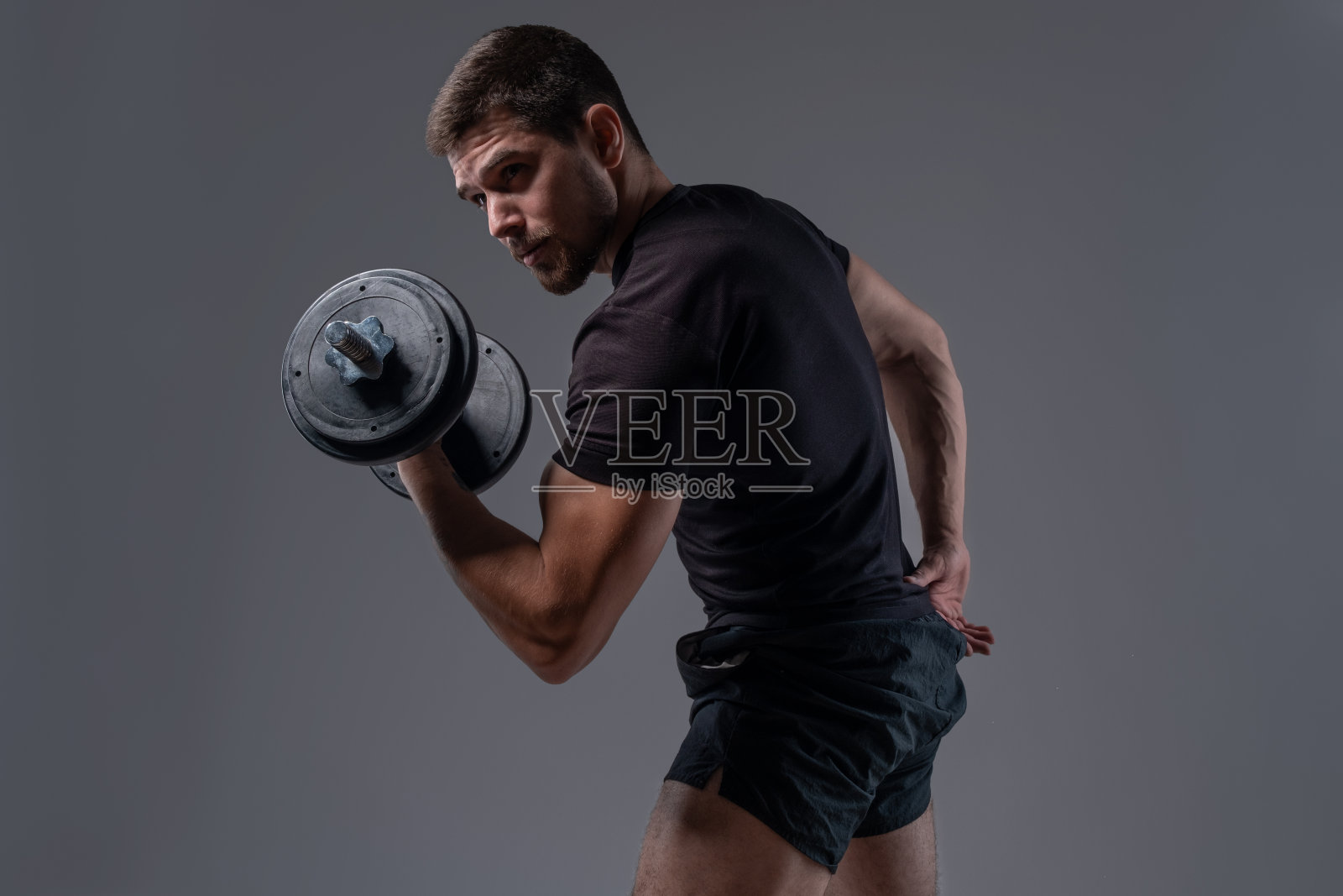 专注的强壮的家伙用哑铃表演二头肌卷照片摄影图片