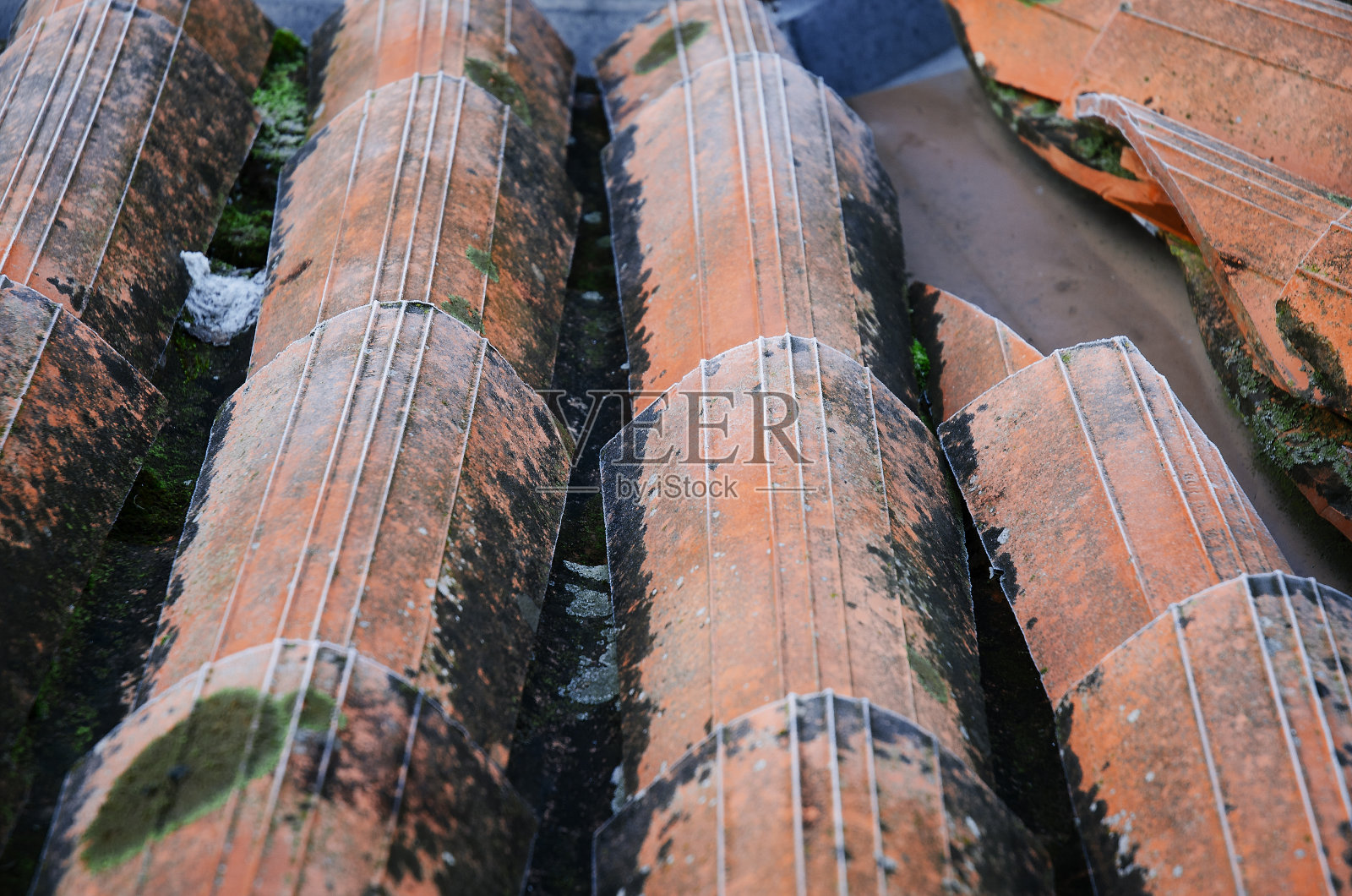 旧的霜冻屋顶瓦片碎片。房子的屋顶,旧风化的肮脏的红色瓦片靠近。复古瓷砖作为背景。照片摄影图片