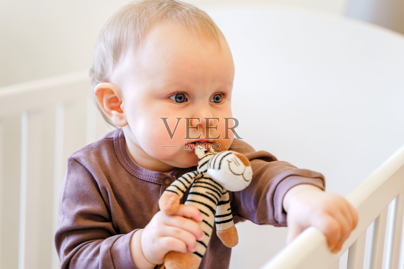 在明亮的房间里,一个可爱的婴儿抱着婴儿床照片摄影图片