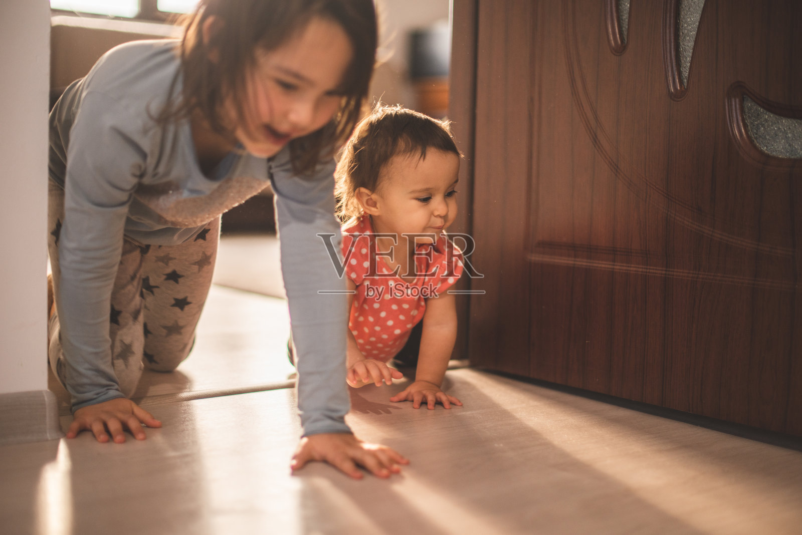 女孩在家里和她的小妹妹玩。他们有乐趣时,所有的四脚行走照片摄影图片