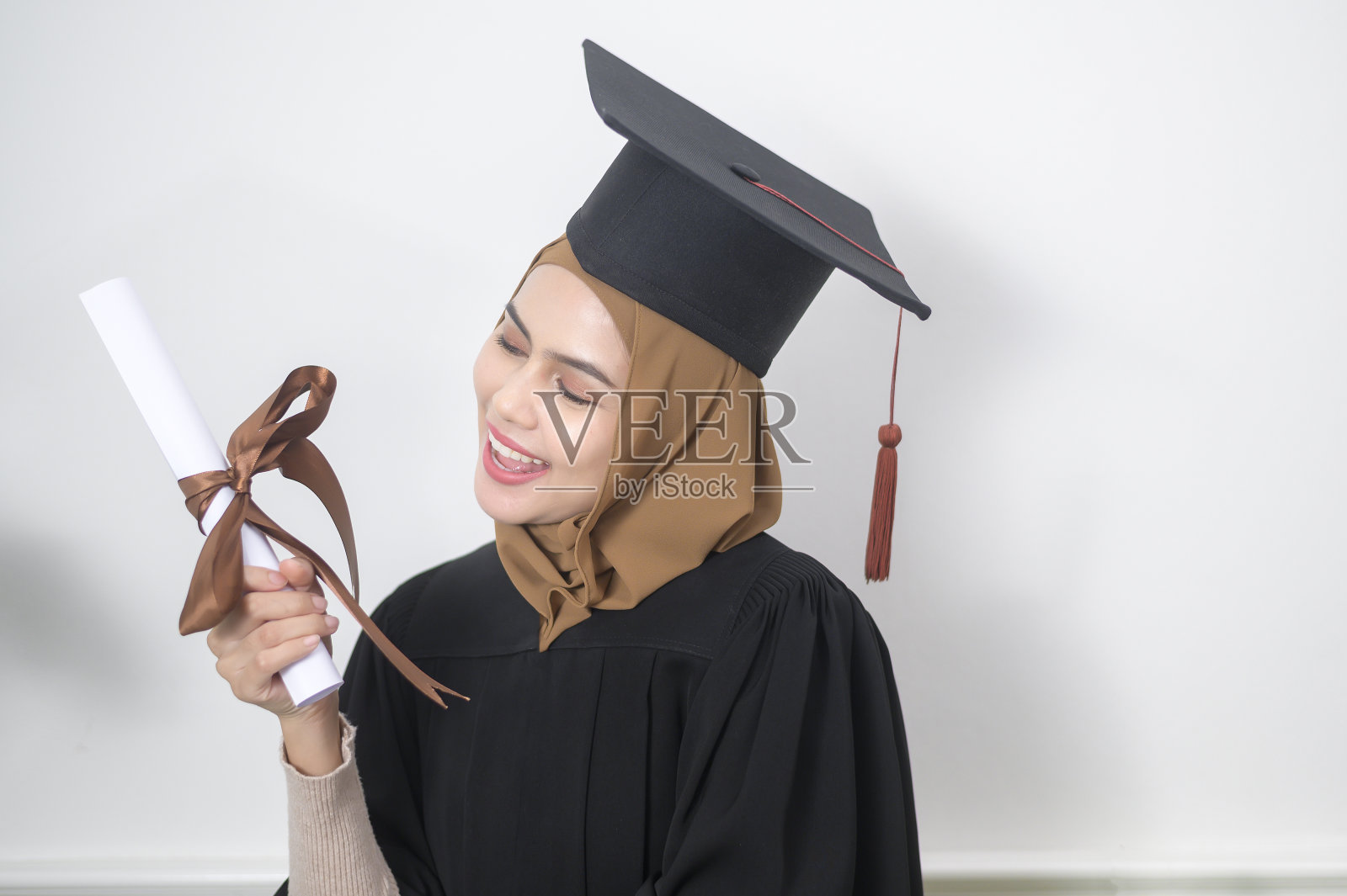 一名年轻的穆斯林女子获得了毕业证书。照片摄影图片