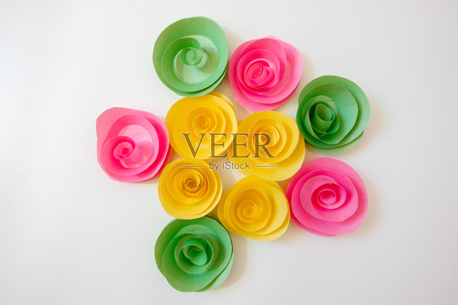 一组纸花(黄、绿、粉)躺在一个明亮的背景上。照片摄影图片