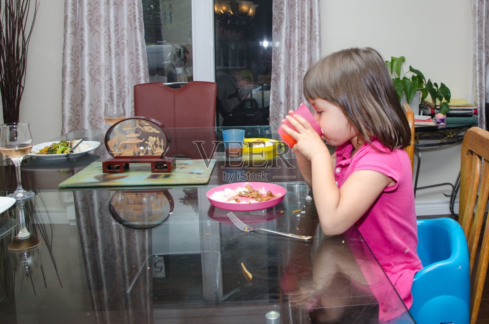 混血小女孩在家里吃晚饭时喝果汁照片摄影图片