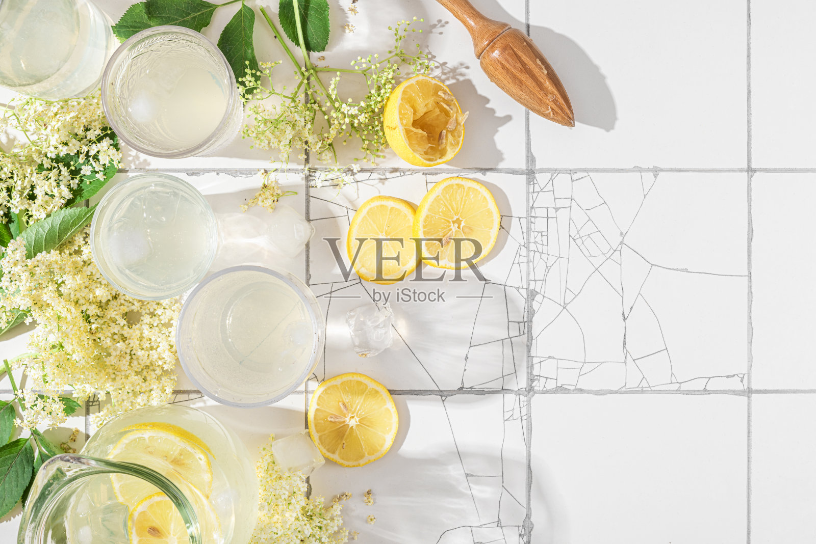 新鲜的冰鸡尾酒或柠檬柠檬和接骨木花杯放在白色的瓷砖桌子上,有复印空间。俯视图照片摄影图片