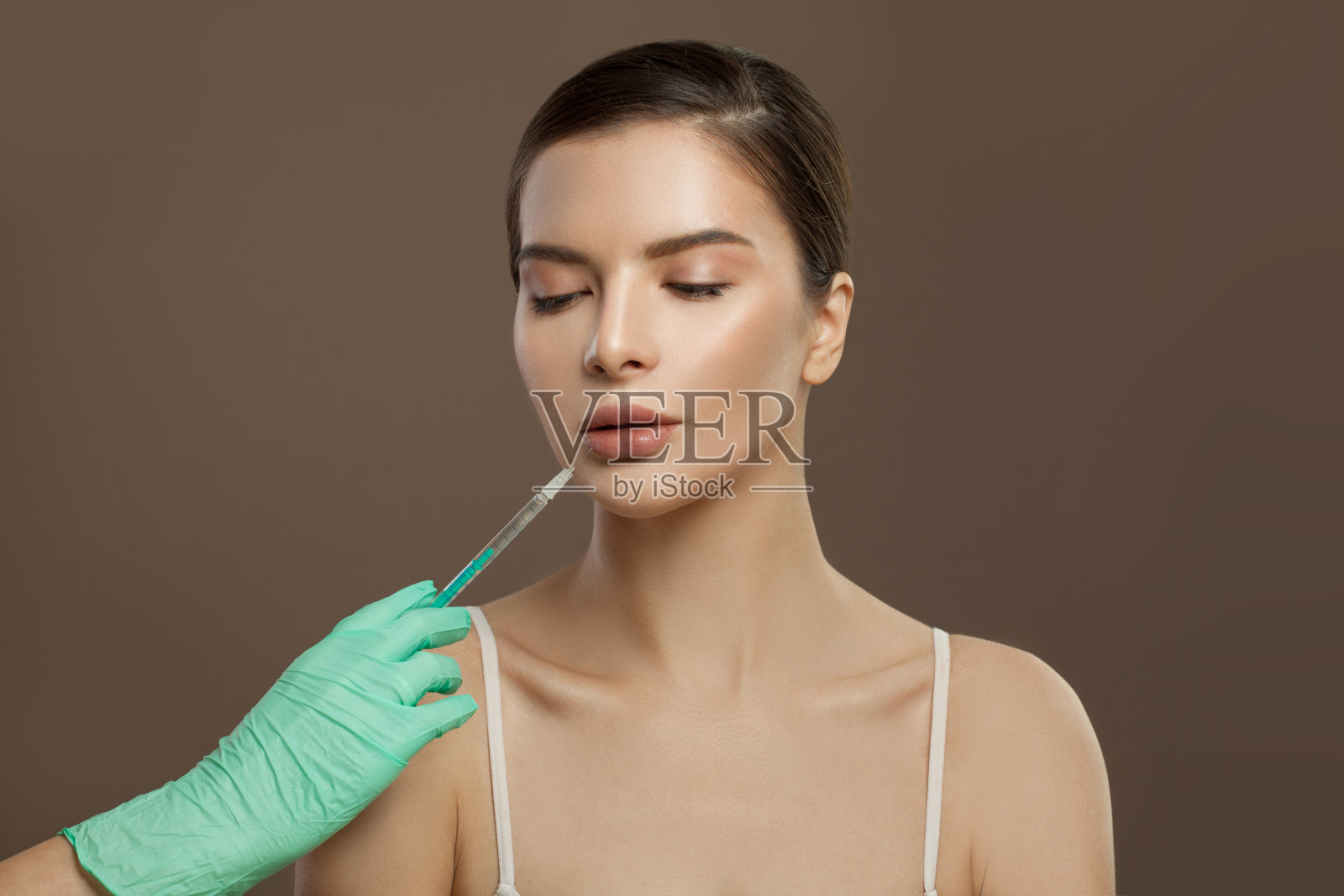 漂亮的女性脸和注射器靠近嘴唇。丰唇美容概念照片摄影图片