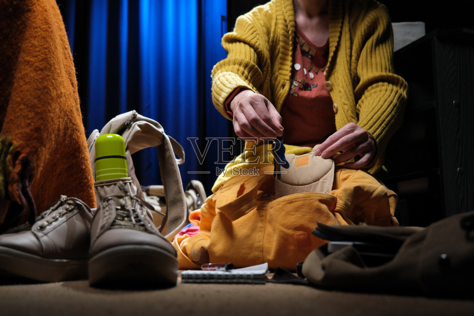 一个女人正坐在家里的地板上,为一次公路旅行打包行李照片摄影图片