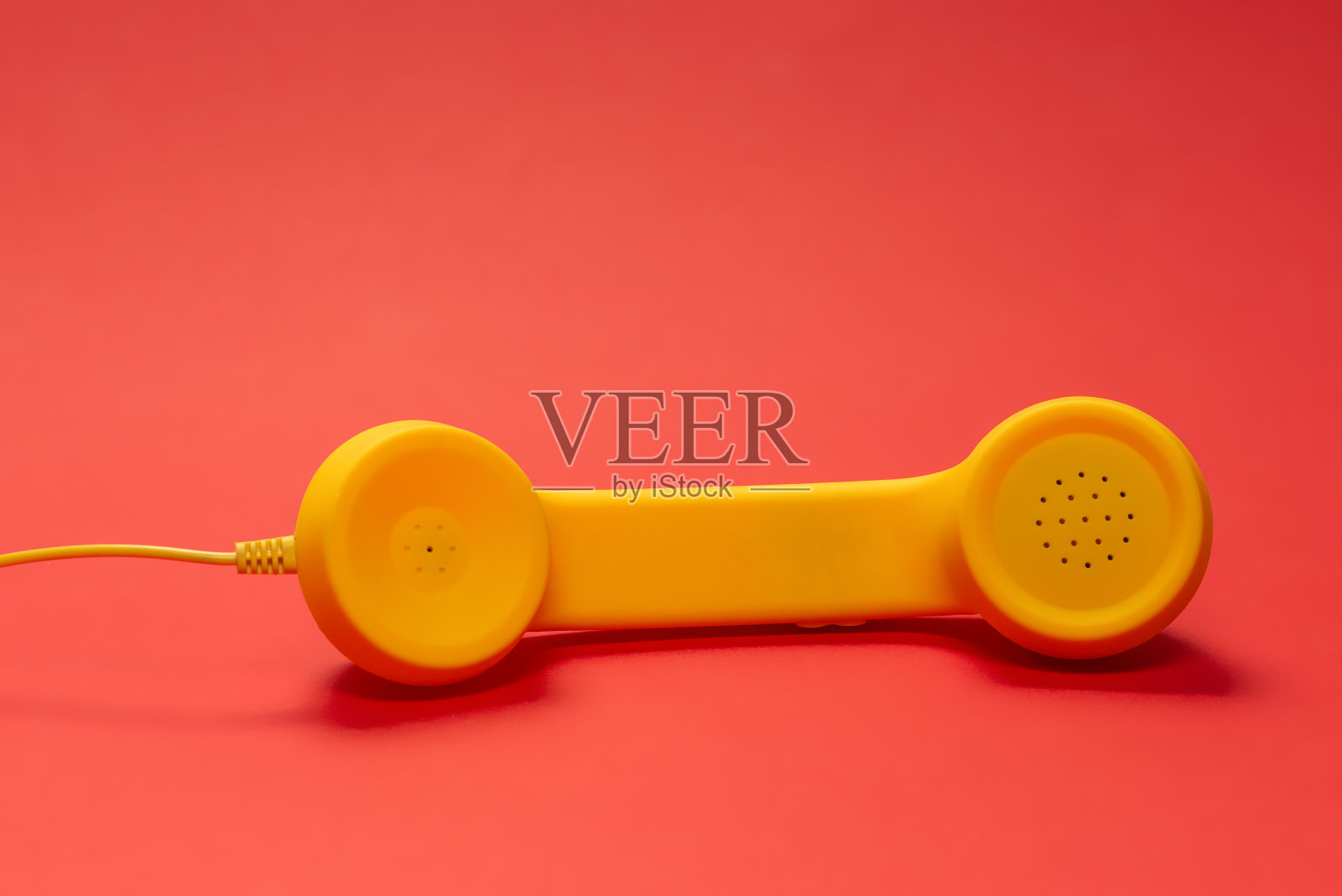 红色背景上的黄色手机。副本的空间。照片摄影图片