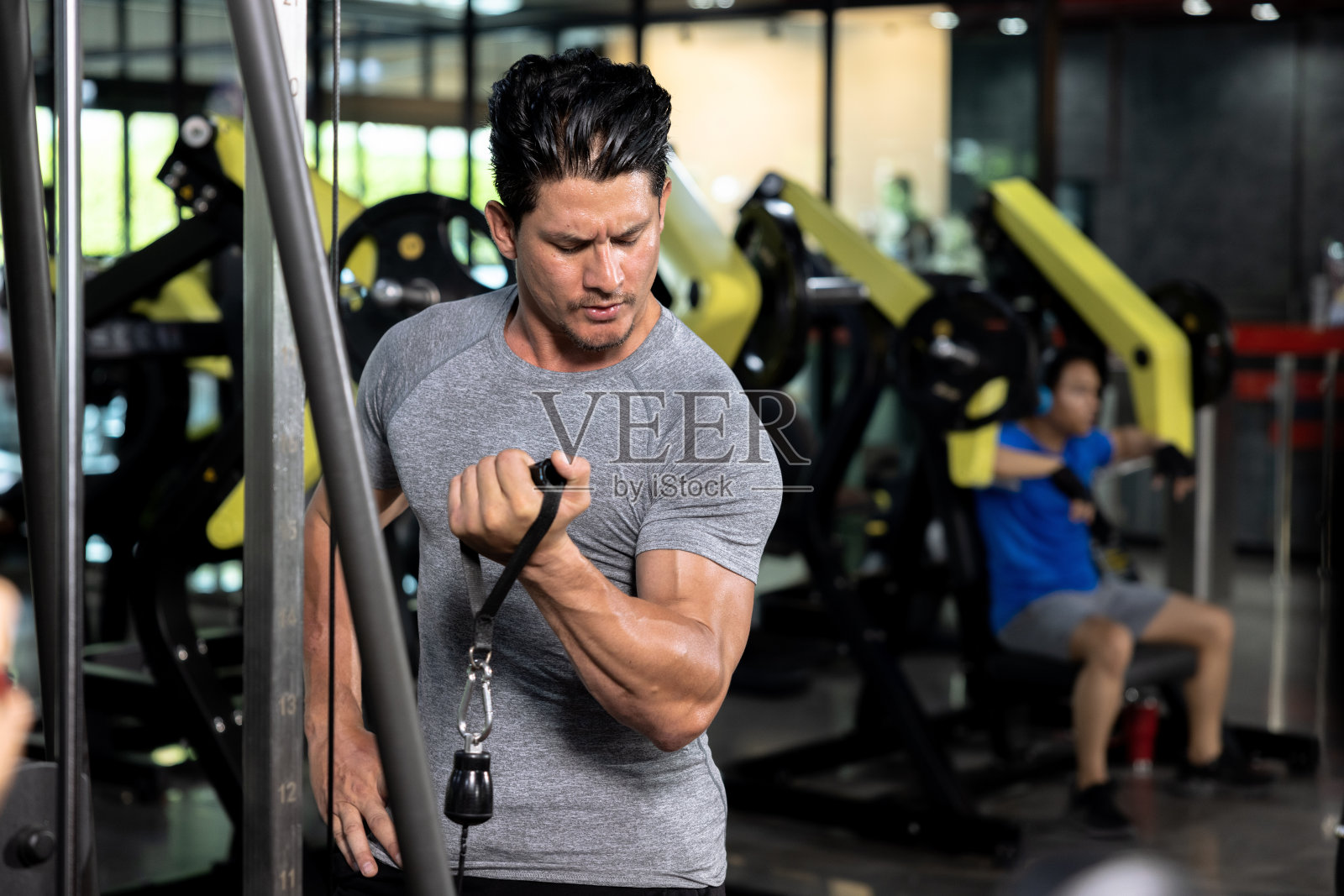 年轻的白人男子训练胸部和上臂交叉机。照片摄影图片