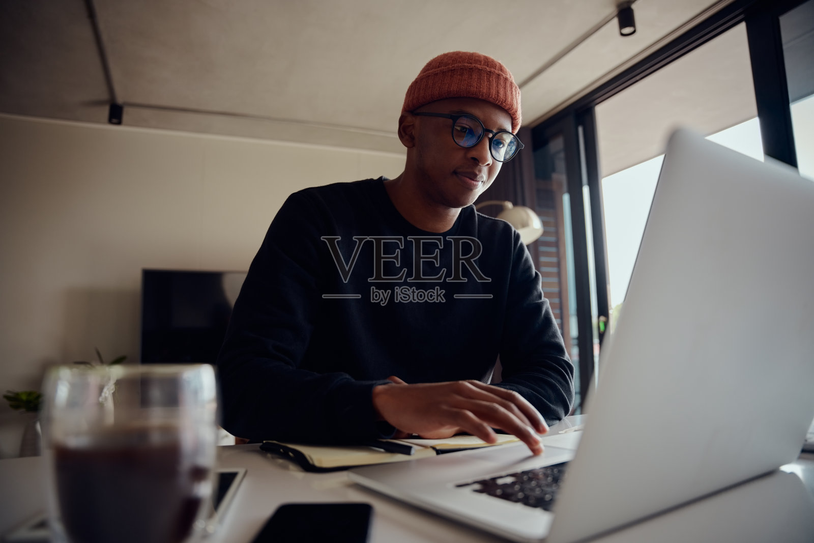 非裔美国男性在家工作,在笔记本电脑上浏览。非裔美国男性在家使用电子产品工作。高质量的照片照片摄影图片