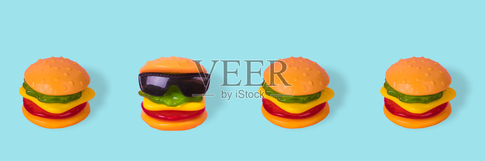 这个创意是用一个汉堡和一排普通汉堡搭配的太阳镜做成的。照片摄影图片