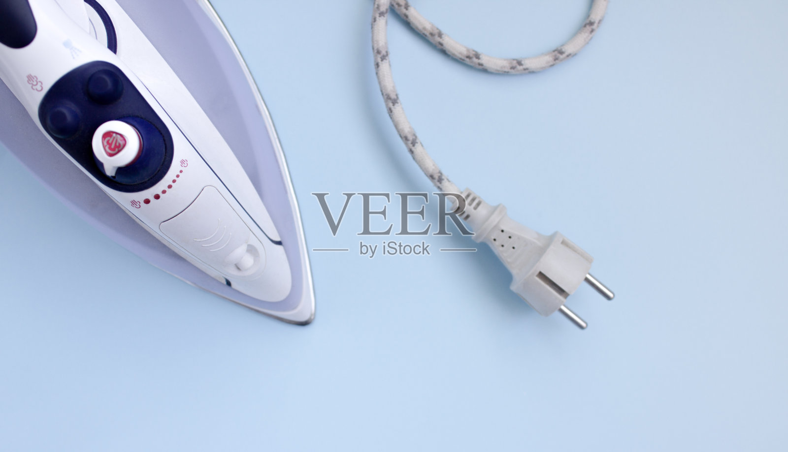 在蓝色背景上熨烫东西的熨斗。俯视图,复制空间照片摄影图片