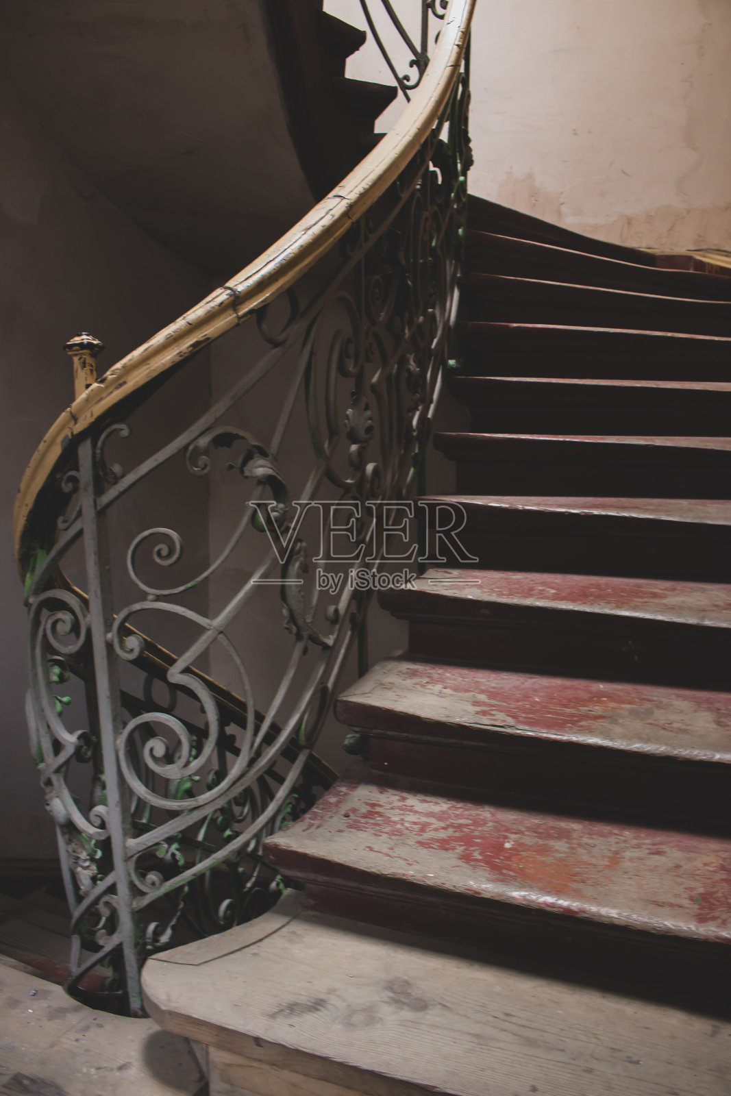 带有铁栏杆的老式木楼梯。废弃历史建筑中的旧圆形楼梯。螺旋楼梯。空的室内楼梯。复古的建筑细节。照片摄影图片