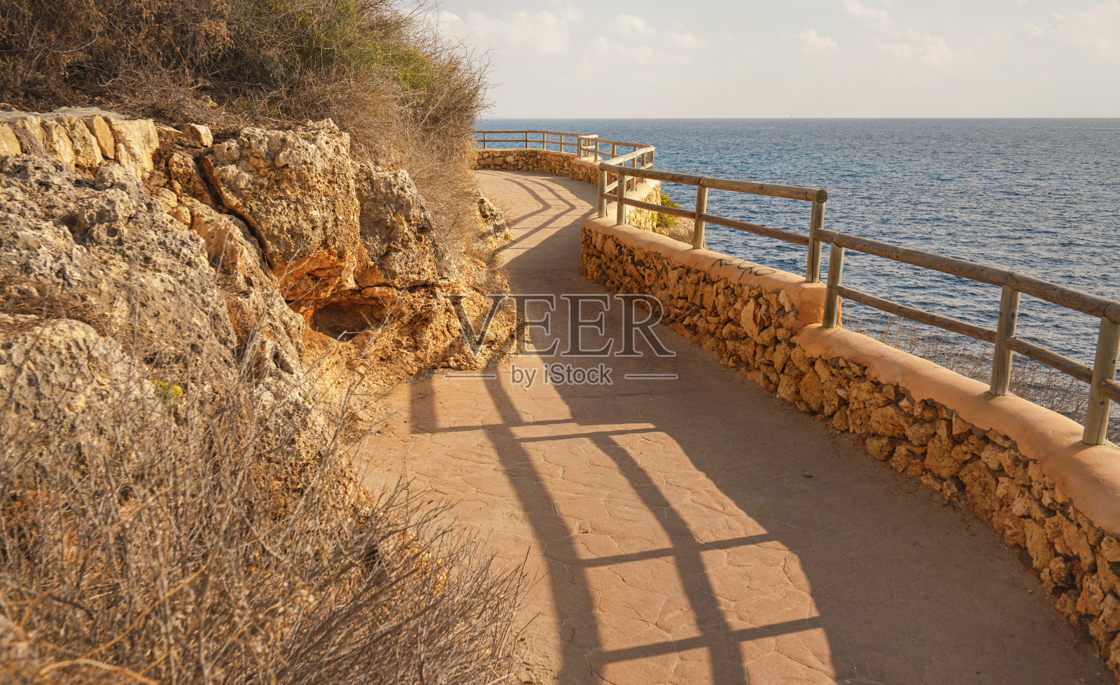 有木栅栏的石路由海边悬崖被晨光照亮照片摄影图片