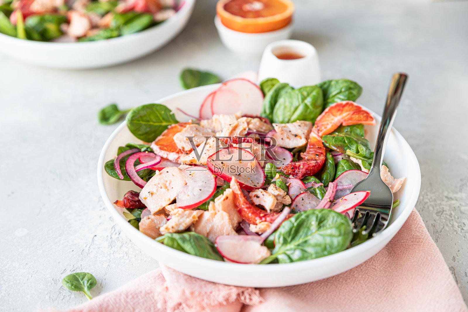 新鲜的沙拉配三文鱼,菠菜,萝卜和红橙,配橙汁,清淡的混凝土背景。照片摄影图片