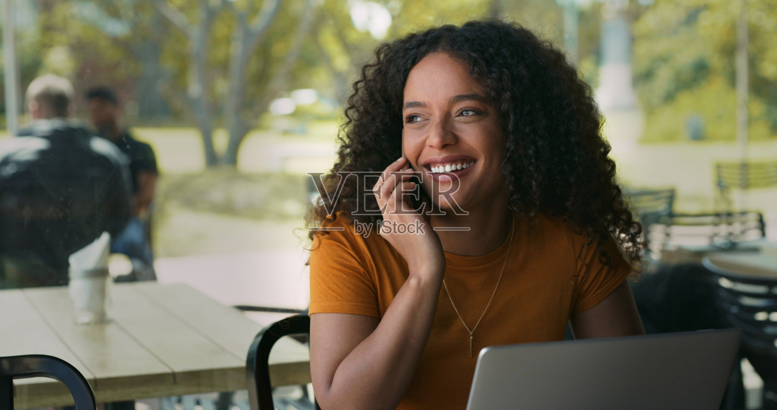 一个女人坐在咖啡店里用手提电脑打电话的照片照片摄影图片