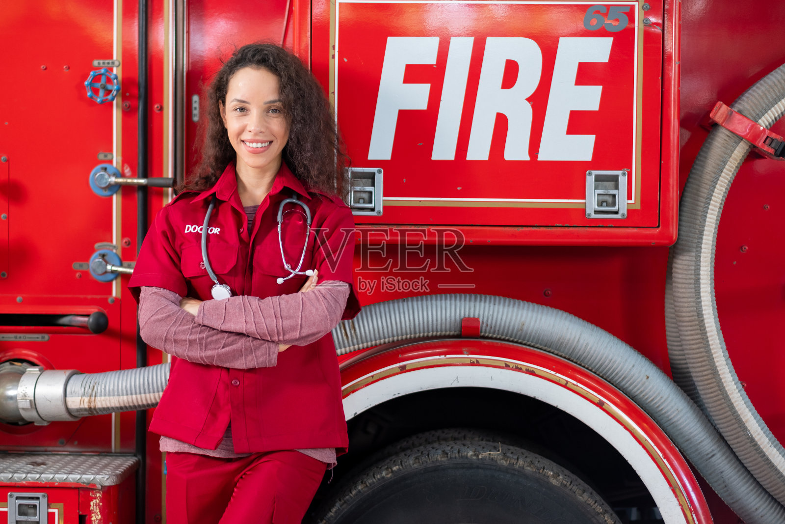 美丽的急诊女医生站在和瘦消防车微笑照片摄影图片