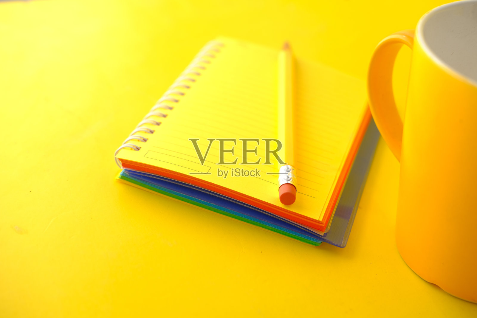 黄色的笔记本和铅笔放在黄色的桌子上照片摄影图片