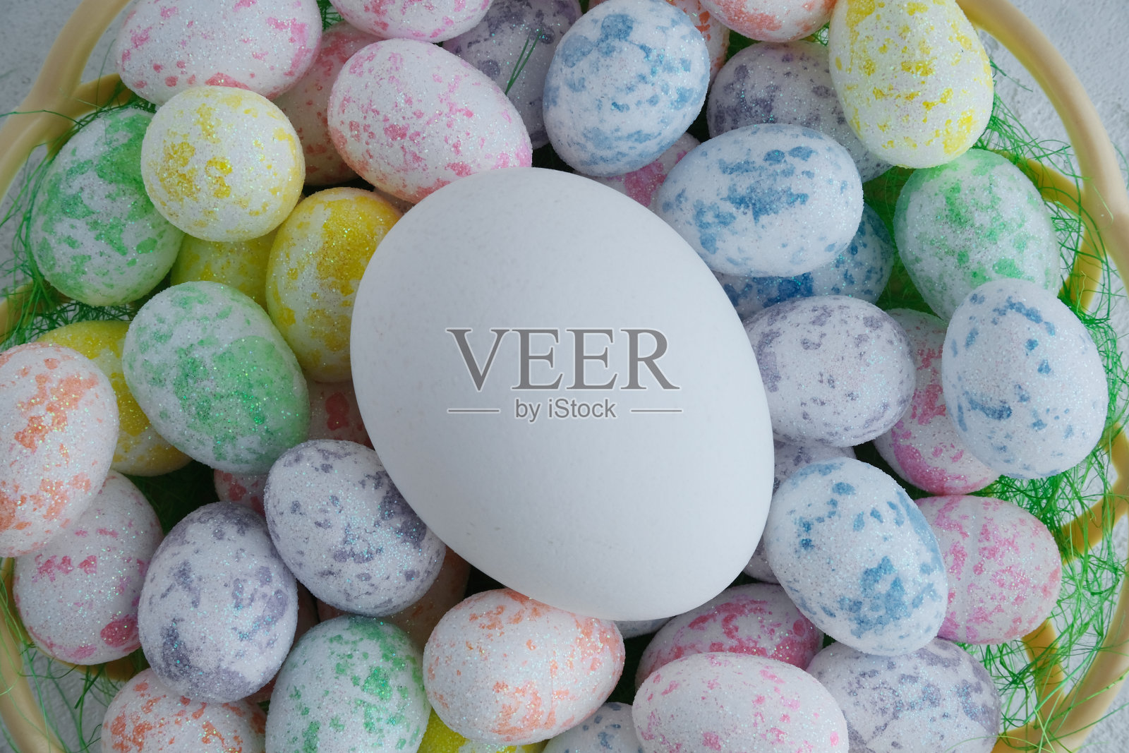 白色的蛋在五颜六色的蛋中。照片摄影图片