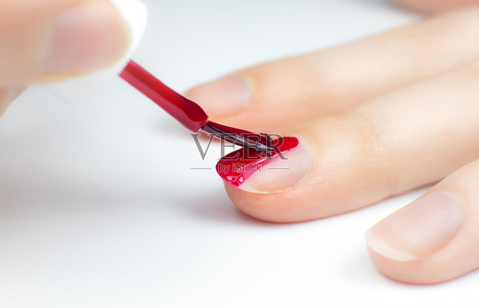 女人涂红色指甲油。做美甲的女孩。沙龙程序在家。漂亮的手和指甲。特写,微距照片。照片摄影图片