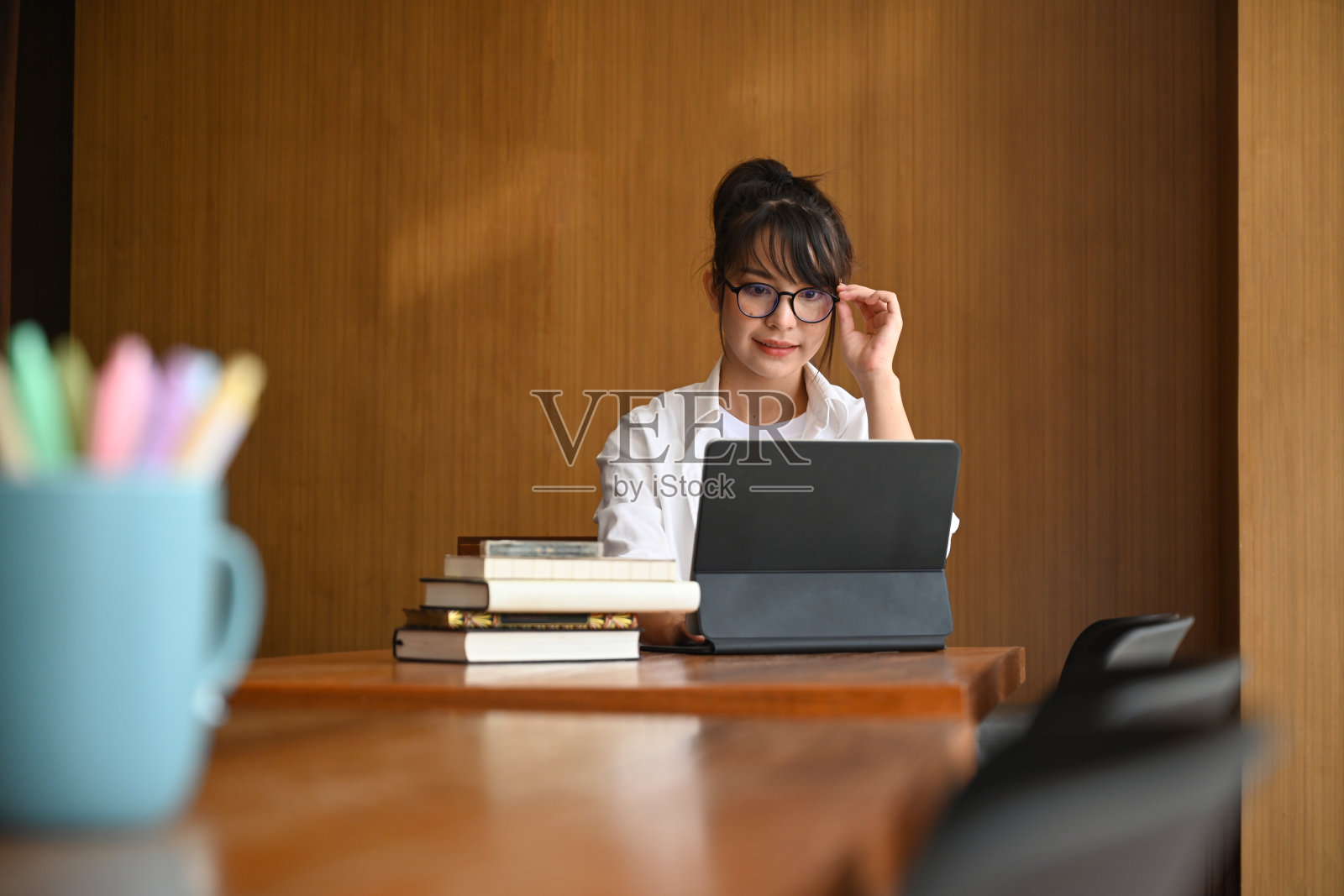 年轻女子戴眼镜,在图书馆使用电脑桌。照片摄影图片