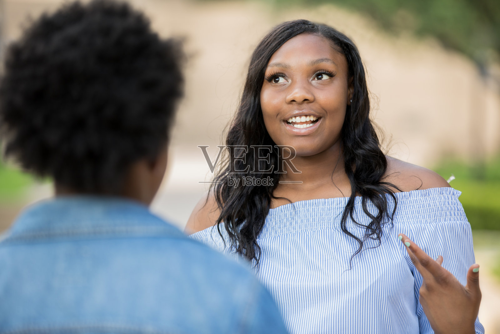 一位年轻的成年女性在校园里和她的朋友在户外交谈照片摄影图片